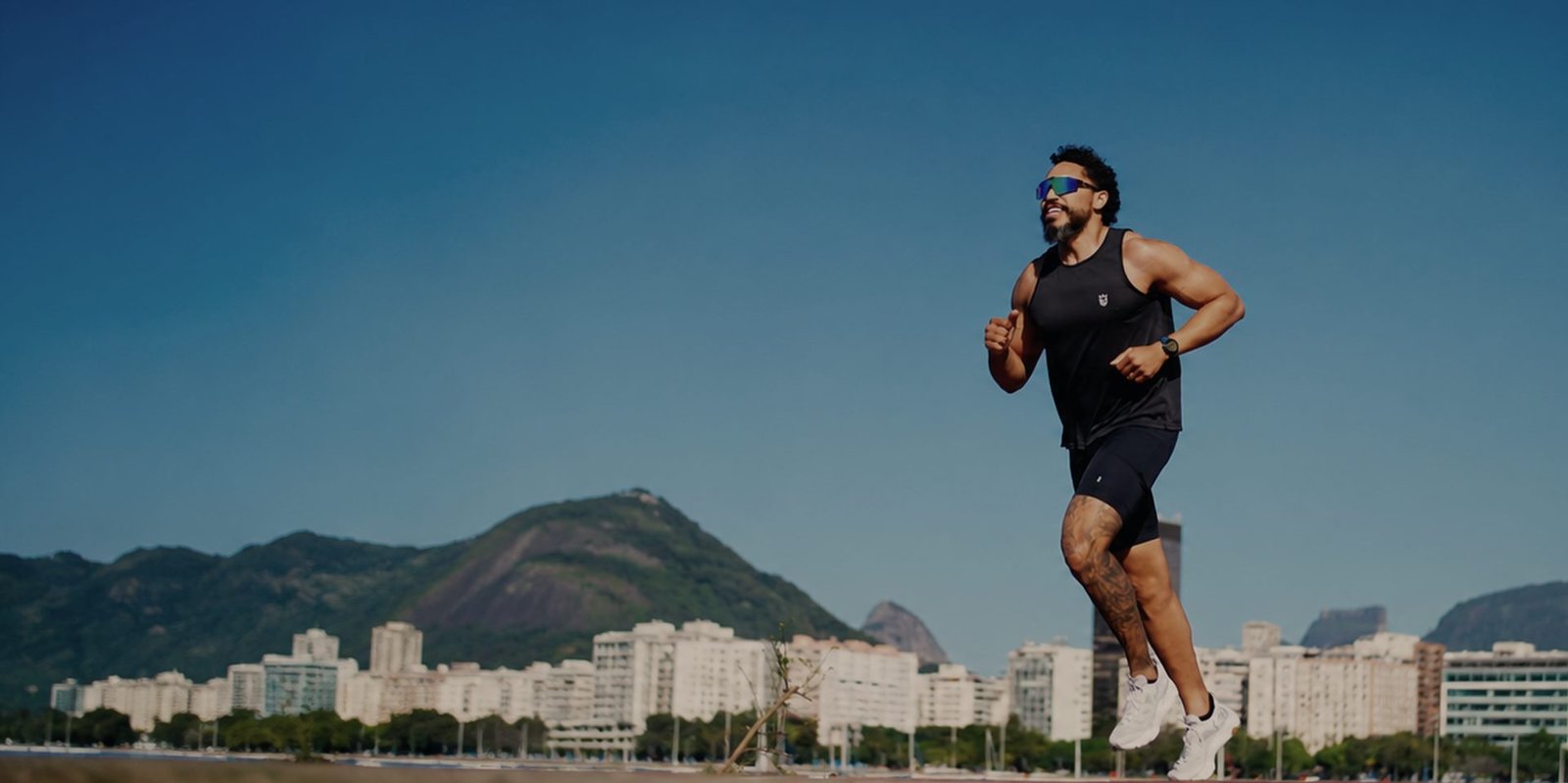 Rodrigo Victor correndo no Aterro do Flamengo, com a orla e as montanhas do Rio de Janeiro ao fundo